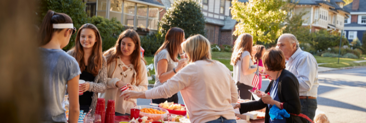 jeunes et adultes en train de célébrer la fête des voisins autour d'un buffet