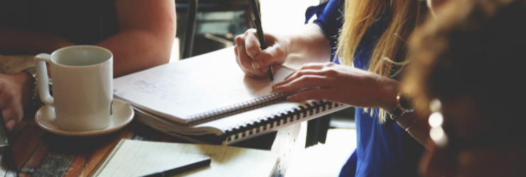 3 personnes dont une écrivant sur un cahier représentant les copropriétaires listant les arguments pour motiver un changement de syndic