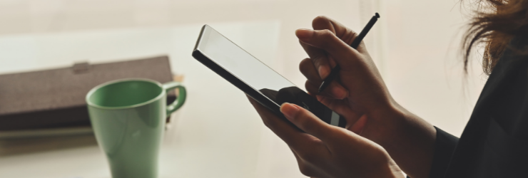 Une femme avec un stylet devant son téléphone représentant la signature d'un mandat de gestion locative en ligne