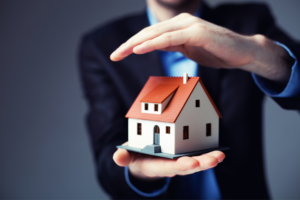 Des mains entourent une maison miniature