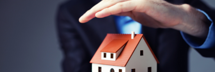 Image avec un fausse maison et une personne mettant sa main au dessus représentant la protection d'une assurance en copropriété