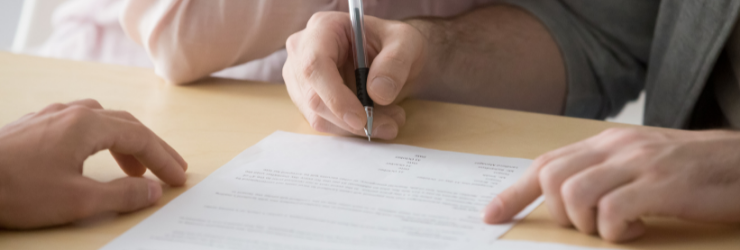 Une personne signant un papier représentation un bailleur qui fait signer le contrat de location à ses locataires.