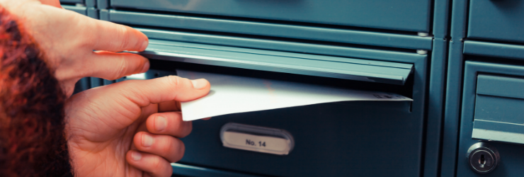 Une personne glissant un courrier dans une boite aux lettres représentant le syndic qui distribue le procès verbal d'assemblée générale.