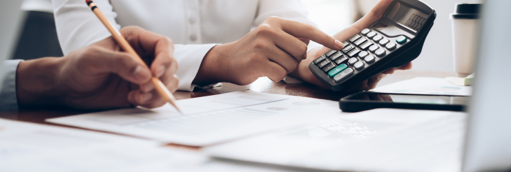 2 personnes avec une calculatrice représentant un propriétaire qui calcule le montant de l'exonération de la taxe sur la plus-value immobilière en cas de vente de son logement