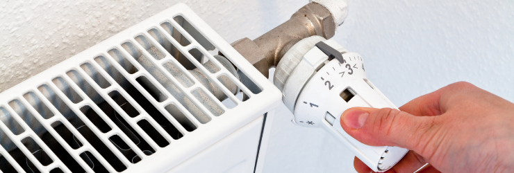 Une main réglant un radiateur représentant l'individualisation des frais de chauffage en copropriété avec la loi ELAN