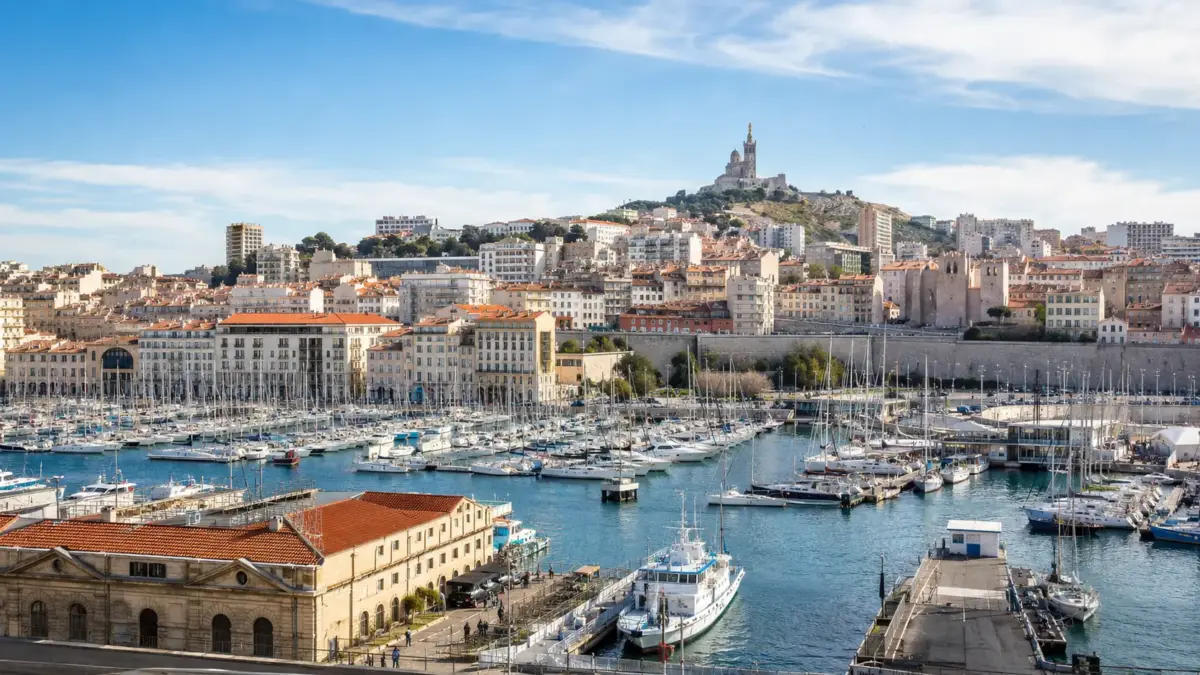 Panorama de Marseille avec le Vieux-Port, ses nombreux bateaux et Notre-Dame de la Garde en arrière-plan sous un ciel dégagé